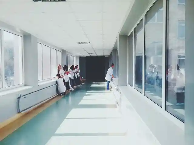 Ärztinnen und Ärzte im Gespräch auf einem lichtdurchfluteten Klinikflur mit Glasfronten