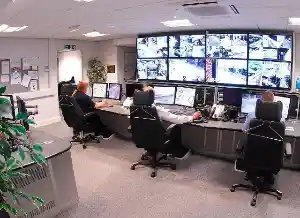 Control room with several monitors for video surveillance, two staff members watching the screens